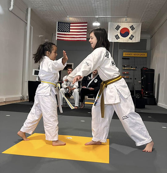 Two young students practicing a block in class